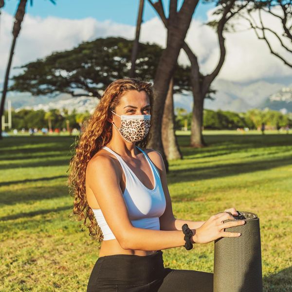 Smiling woman stretching gently on a yoga mat outdoors.
